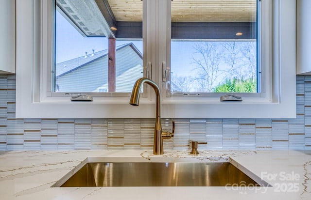 room details featuring light stone countertops, sink, and backsplash