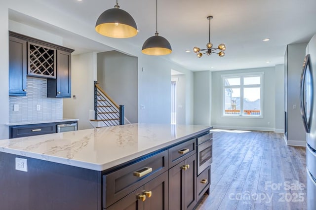 kitchen with hanging light fixtures, appliances with stainless steel finishes, a kitchen island, and tasteful backsplash