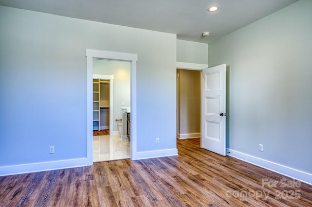 unfurnished bedroom featuring a walk in closet, a closet, and wood-type flooring