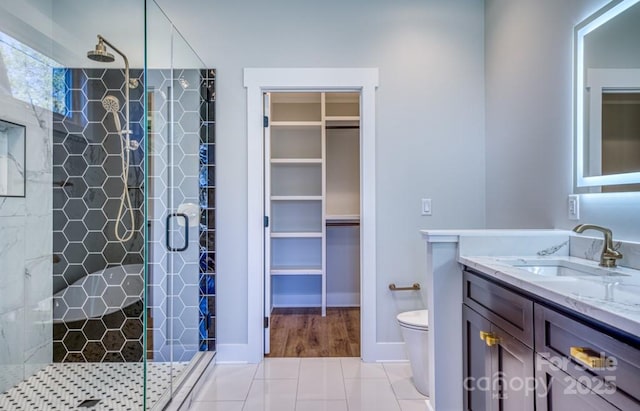 bathroom featuring tile patterned floors, a shower with door, toilet, and vanity