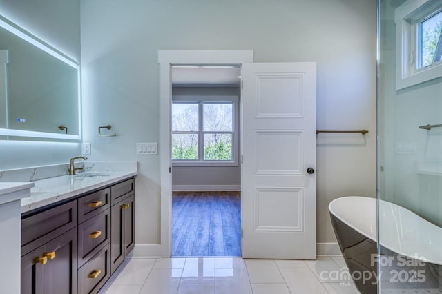 bathroom with tile patterned floors, a washtub, and vanity