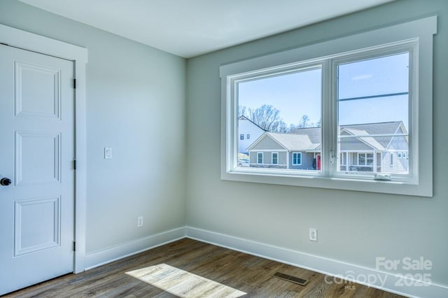 unfurnished room featuring dark wood-type flooring and a wealth of natural light