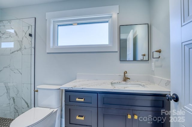 bathroom featuring toilet, vanity, and a tile shower