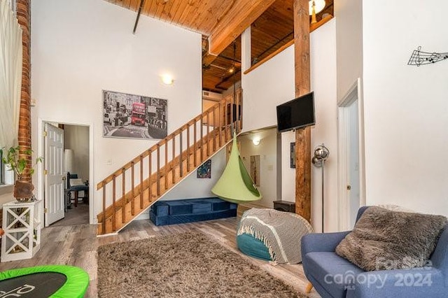 interior space featuring a towering ceiling, wood ceiling, beamed ceiling, and wood-type flooring