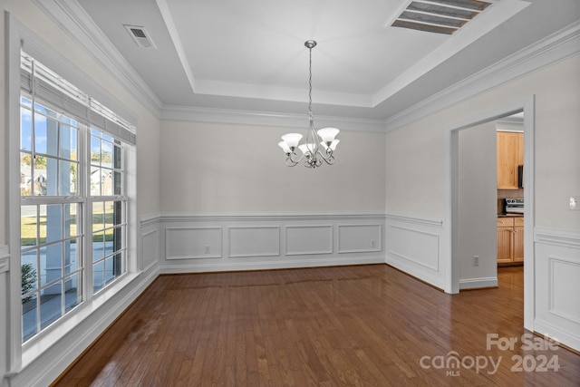 unfurnished dining area with dark hardwood / wood-style flooring, ornamental molding, a tray ceiling, and an inviting chandelier