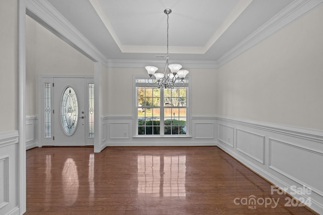 foyer featuring a chandelier, wood-type flooring, a raised ceiling, and crown molding