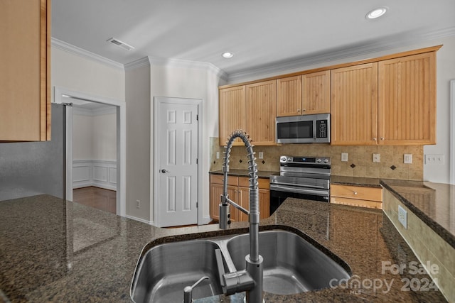 kitchen with sink, backsplash, dark stone countertops, appliances with stainless steel finishes, and ornamental molding