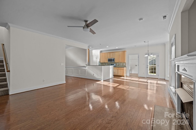 unfurnished living room featuring crown molding, ceiling fan with notable chandelier, and light wood-type flooring