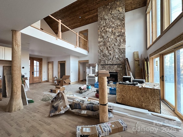 living room featuring french doors, a fireplace, wood finished floors, and a high ceiling