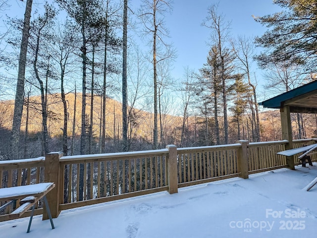 snow covered deck with a view of trees