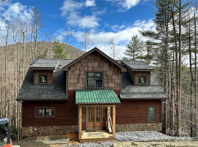 rustic home featuring stone siding, roof with shingles, and french doors