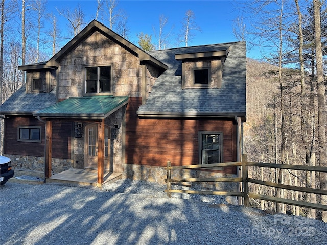 view of front of house with roof with shingles and fence