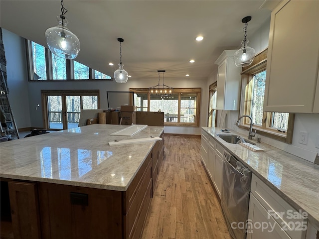 kitchen with light wood finished floors, white cabinets, a large island, a sink, and stainless steel dishwasher