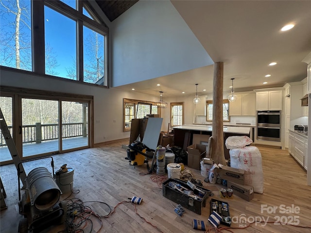 living room with baseboards, a towering ceiling, light wood-style flooring, and recessed lighting