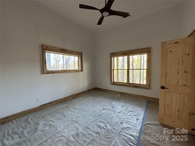 spare room featuring lofted ceiling, a healthy amount of sunlight, ceiling fan, and baseboards