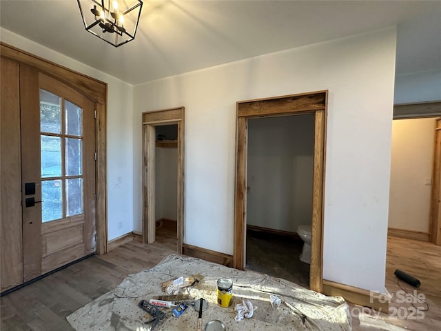 interior space featuring a notable chandelier, baseboards, and wood finished floors