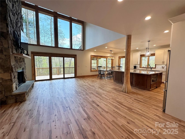 371 Hews Cir, Blowing Rock, NC 28605 - living room featuring healthy amount of natural light, light wood-type flooring, recessed lighting, a stone fireplace, and a high ceiling