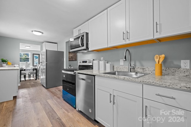 kitchen featuring sink, stainless steel appliances, white cabinets, light stone counters, and light hardwood / wood-style flooring