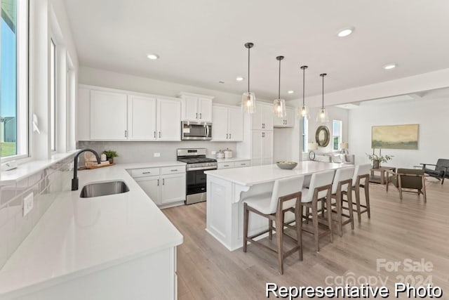 kitchen with sink, a center island, stainless steel appliances, pendant lighting, and white cabinets