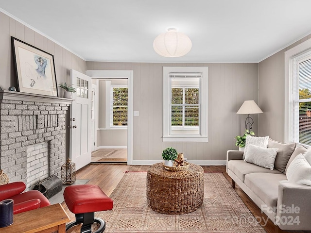 living room with a fireplace, crown molding, plenty of natural light, and hardwood / wood-style flooring