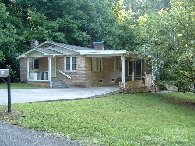 view of front of home with a front lawn, a porch, and a carport