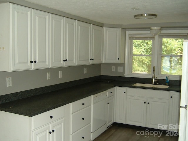 kitchen with white cabinets, white dishwasher, dark wood-type flooring, and sink