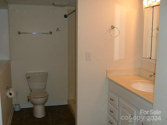 bathroom featuring toilet, vanity, tile patterned floors, and walk in shower