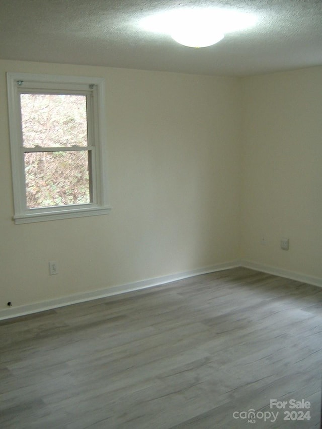 spare room with a textured ceiling and light hardwood / wood-style flooring