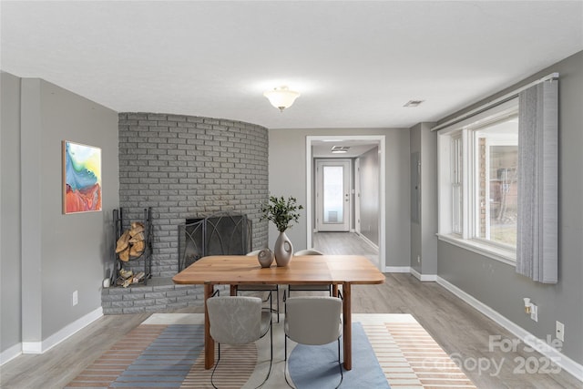 dining room with a brick fireplace and light wood-type flooring