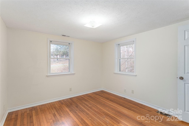 empty room featuring hardwood / wood-style flooring and a textured ceiling