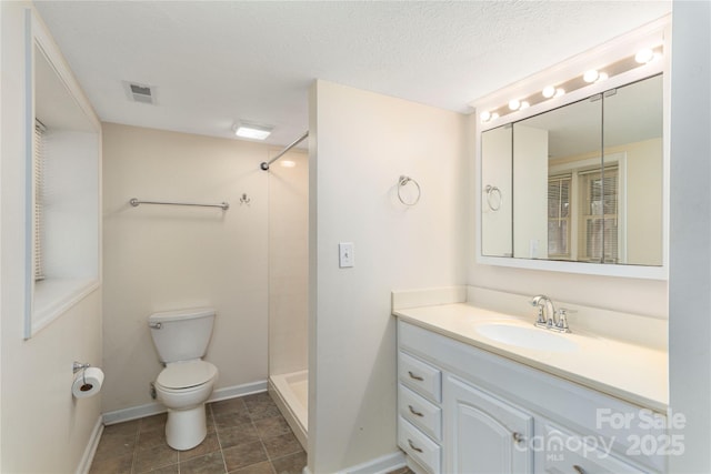 bathroom featuring toilet, vanity, a textured ceiling, and walk in shower