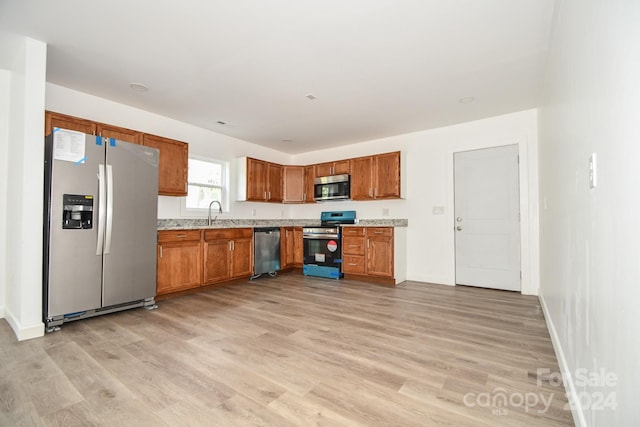 kitchen with stainless steel appliances, sink, and light wood-type flooring