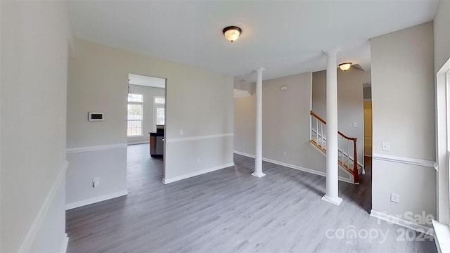 empty room featuring hardwood / wood-style floors and decorative columns