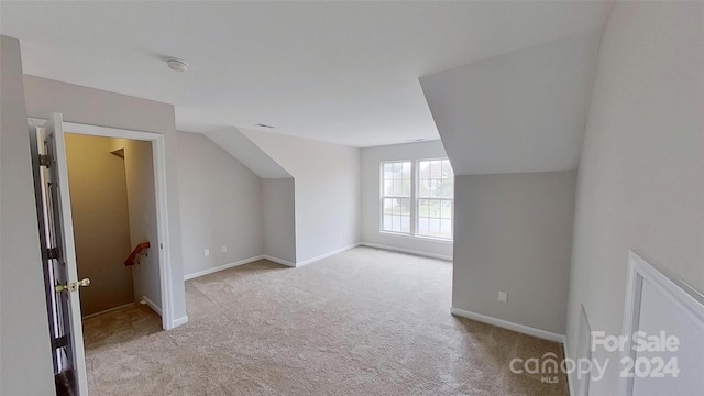 bonus room with light carpet and vaulted ceiling