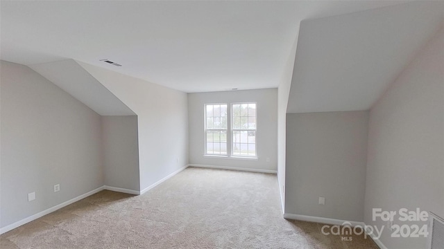 bonus room with lofted ceiling and light carpet