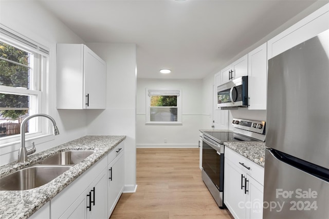 kitchen with light wood-type flooring, appliances with stainless steel finishes, sink, and white cabinets