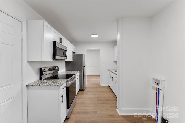 kitchen featuring white cabinetry, light stone counters, light hardwood / wood-style floors, and stainless steel appliances