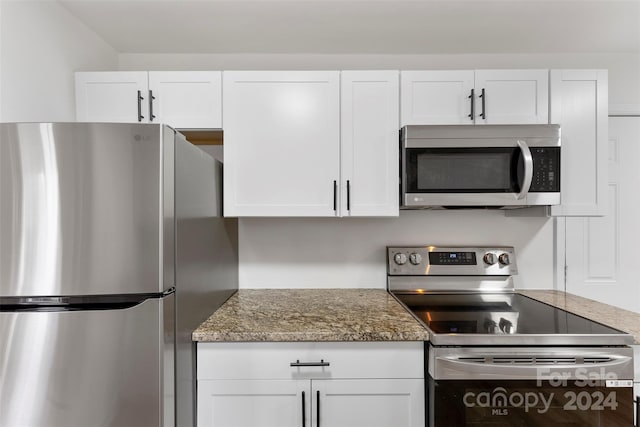 kitchen with white cabinets, appliances with stainless steel finishes, and stone countertops