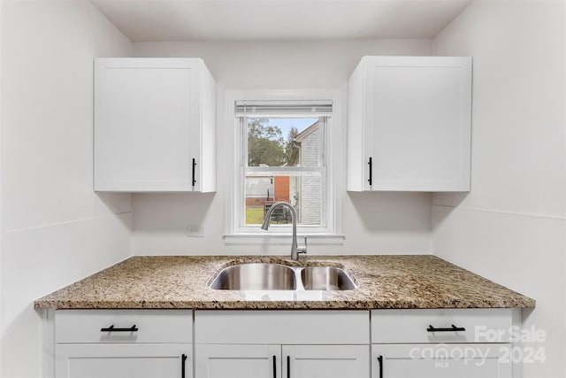 kitchen with white cabinetry, sink, and stone countertops