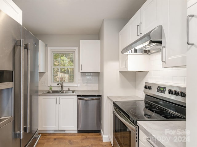 kitchen featuring sink, white cabinetry, stainless steel appliances, and range hood