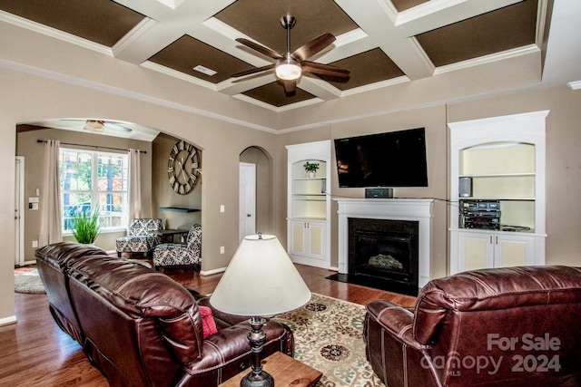 living room with ceiling fan, coffered ceiling, wood-type flooring, and crown molding