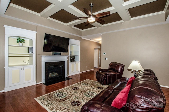 living room featuring coffered ceiling, dark wood-type flooring, crown molding, built in shelves, and ceiling fan