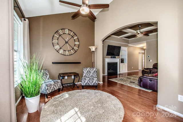 living room with beam ceiling, coffered ceiling, wood-type flooring, and ceiling fan