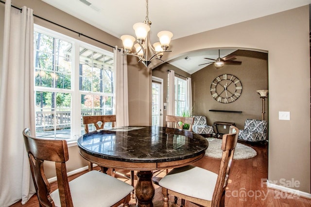 dining area featuring hardwood / wood-style floors, ceiling fan with notable chandelier, and vaulted ceiling