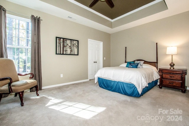 bedroom with crown molding, light colored carpet, a tray ceiling, and ceiling fan