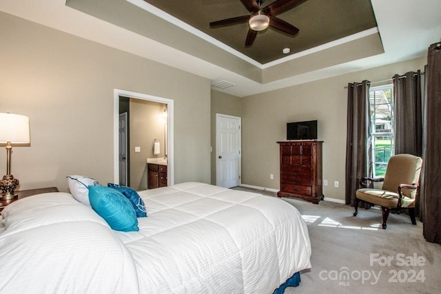 bedroom featuring ceiling fan, light carpet, a tray ceiling, and ensuite bath