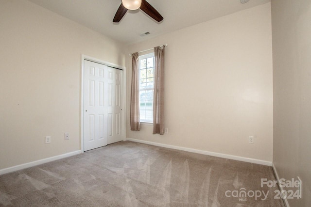 unfurnished bedroom with a closet, carpet floors, and ceiling fan