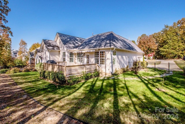 rear view of house featuring a wooden deck and a lawn