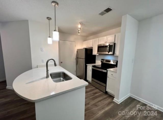 kitchen with sink, pendant lighting, white cabinetry, appliances with stainless steel finishes, and dark hardwood / wood-style flooring