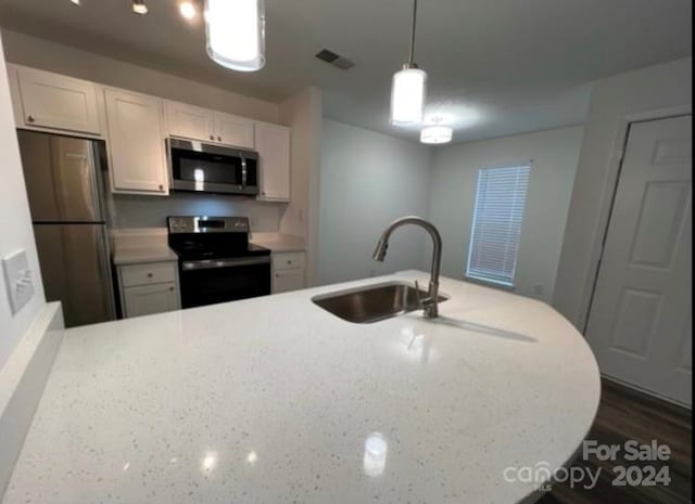 kitchen with sink, white cabinetry, hanging light fixtures, and stainless steel appliances